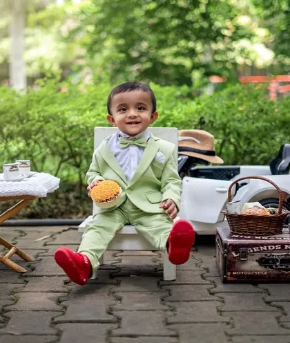 A dapper little gentleman enjoying an outdoor tea party. The combination of a smart suit and a natural setting creates a unique and charming portrait.