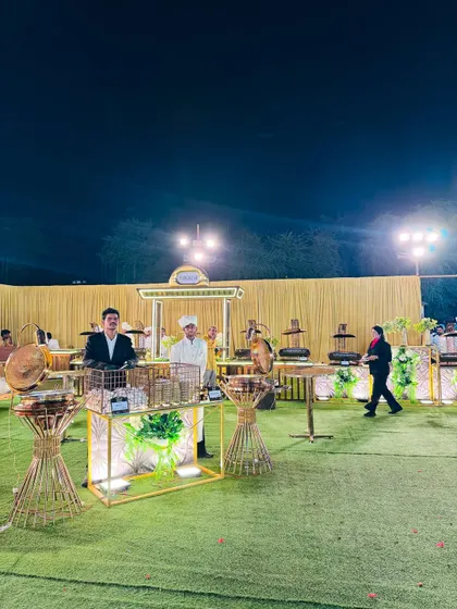 A wide shot of an outdoor event space, showing multiple food counters and guest seating areas.