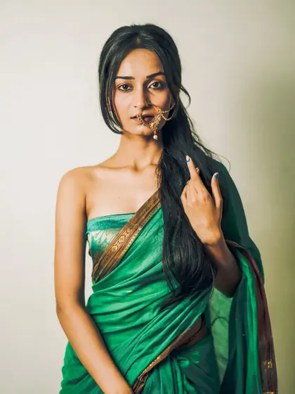 A modern take on a traditional look, this portrait features a model in a strapless green saree, showcasing her long hair and elegant nath.