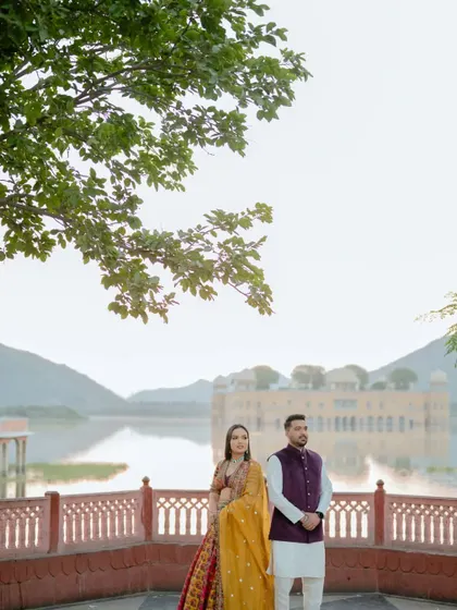 We use iconic Jaipur landmarks like Jal Mahal to create breathtaking backdrops. This photo shows a couple standing against the serene lake and palace, demonstrating how we incorporate famous scenery into your love story.
