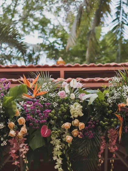 A close-up of the lush, tropical floral arrangements used to adorn the mandap. We used a mix of birds of paradise, roses, and orchids to create a vibrant and textured look that stands out against the green foliage.
