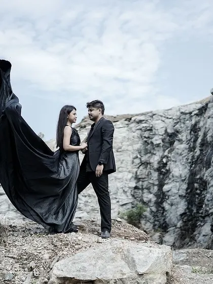 An intimate yet powerful pose amidst a rocky landscape, with the bride's black gown creating a striking silhouette.