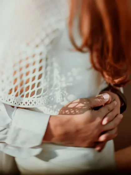 A close-up shot of hands intertwined, with beautiful dappled light creating patterns on the skin. This artistic detail from a Delhi shoot highlights the simple, profound connection of touch.