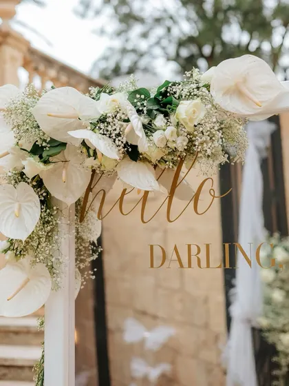 "Hello Darling." A sweet message on a mirror, framed by beautiful white anthuriums and baby's breath, welcomes guests to this elegant white wedding.