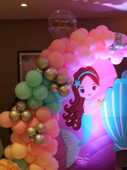 A closer look at the details of our mermaid theme decor. The custom-printed mermaid character and seashell cutouts are paired with a pastel balloon garland to complete the underwater look.