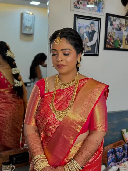 My stunning South Indian bride Abhirami. Her look is defined by the rich red and gold Kanjeevaram saree, traditional gold jewellery, and a classic makeup look with kohl-rimmed eyes.
