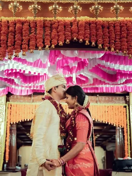 A beautifully framed silhouette of a couple sharing a tender moment under a decorated archway.