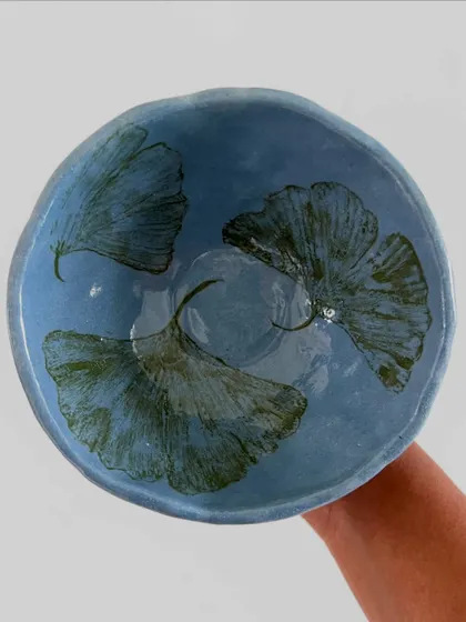 The interior of a student's bowl, beautifully decorated with floating ginkgo leaves against a serene blue background.