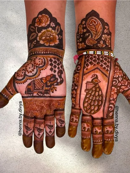A rich design featuring a large elephant on one palm and a peacock on the other. The wrists are decorated with floral patterns and peacock feather motifs.