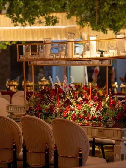 A closer look at the stunning dining table setup. The mirrored surface reflects the overhead red drapes and chandeliers, amplifying the sense of opulence and drama.