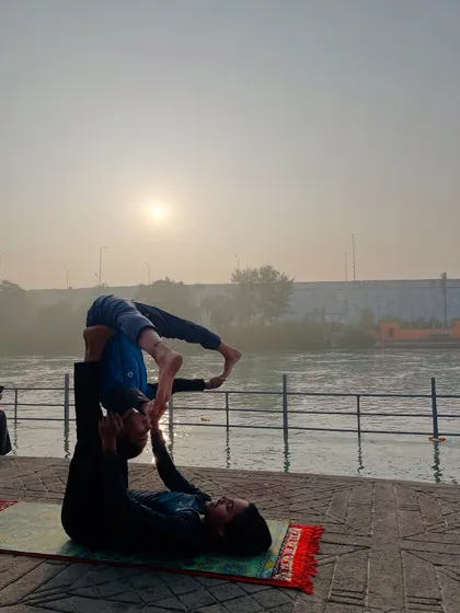 An acroyoga folded leaf pose, a therapeutic posture that helps release the flyer's lower back.