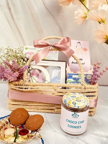 A beautiful jute basket hamper curated specially for sisters. It's filled with skincare goodies, cookies, and a rakhi thali, making it a thoughtful and pampering gift.
