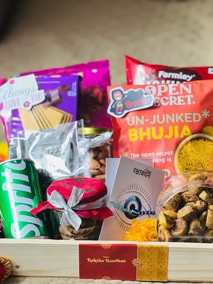 This wooden tray hamper for Rakhi is packed with a variety of snacks and a drink, perfect for a sibling who loves to munch.