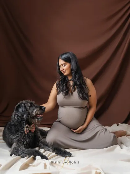 A tender moment in the studio between an expecting mother and her senior dog. The simple brown backdrop keeps the focus entirely on their sweet interaction.