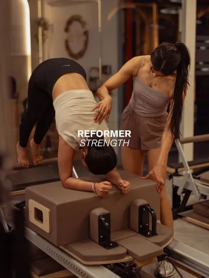 Here, I'm providing a hands on adjustment to ensure proper form during a challenging pike exercise on the reformer box. This personal attention helps you get the most out of every movement safely.