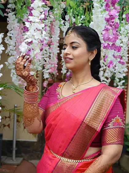 A lovely photo of the bride against a floral backdrop, her henna-stained hands gently touching the flowers.