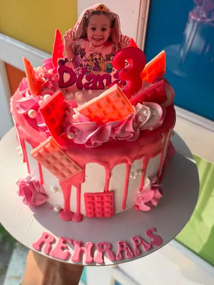 A fun and vibrant pink drip cake for a 3rd birthday, featuring the birthday girl's favorite character.