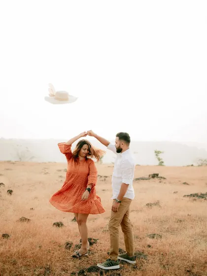 A dynamic and fun shot of the couple dancing in a field, with a hat tossed in the air for a playful touch.