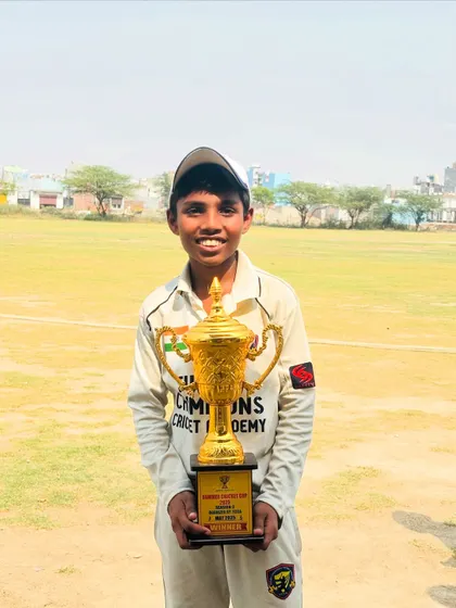 A young champion holding the winner's trophy. This is the dream we help our players achieve.