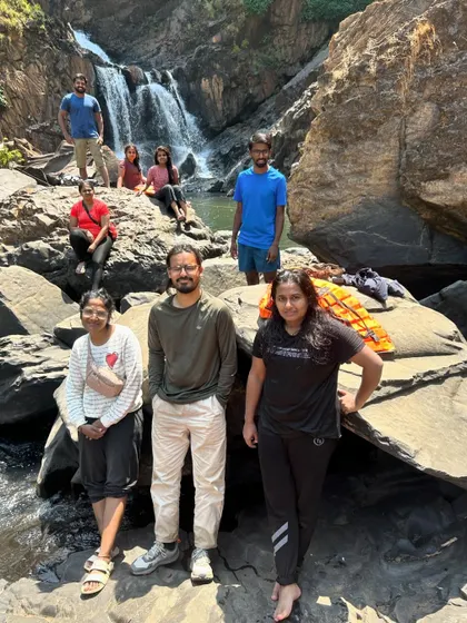 A group relaxing by the rocks near a waterfall. These are the moments to rest, chat, and enjoy the beautiful surroundings.