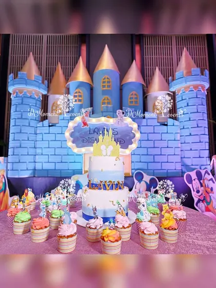The castle stage doubles as a beautiful dessert table, showcasing a themed cake and cupcakes in front of the magical backdrop.