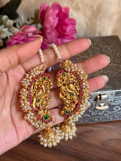 Our traditional Maharashtrian karnful, or ear cuffs, are a beautiful way to adorn your ears. This piece features a classic peacock design with red and green stones, surrounded by delicate pearls, adding a touch of heritage to your look.