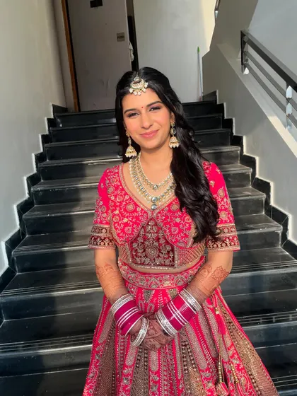 A full-length shot of the bride in her gorgeous pink lehenga. The minimal makeup ensures that her natural beauty and the stunning outfit are the focus.