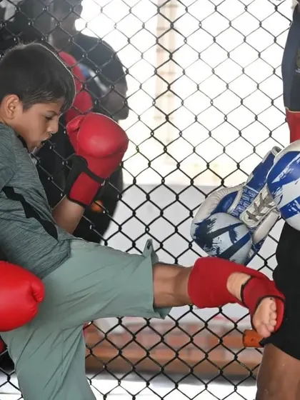 A young fighter throwing a clean kick during a pad work session. The technique and power at such a young age is impressive.
