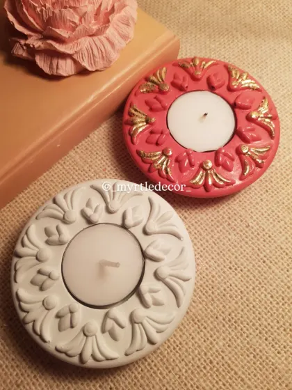 A still shot of our festive T-light holders, one with gold accents and one in a simple, elegant white. They are pictured here with one of our Peony aroma stones.