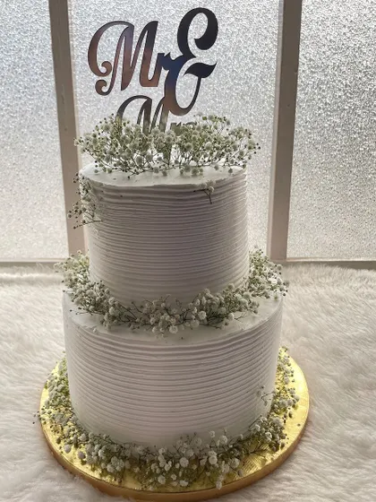 A classic two-tier white wedding cake. The textured frosting and delicate baby's breath give it a timeless and romantic feel, perfect for a reception.