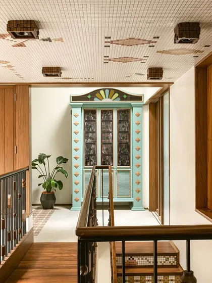 The upper corridor in Kolam Pop, where a custom-painted bar cabinet with stained glass panels stands as a vibrant centerpiece.