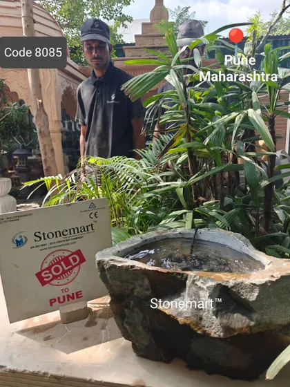 An artisan poses with the sold natural rock birdbath, showing its size and unique, organic shape.