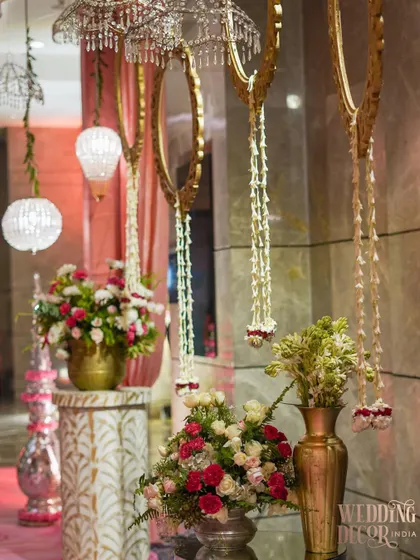 A close-up of entrance decor, showing hanging floral kaleeras, crystal spheres, and ornate golden mirrors. These elements work together to create a rich and celebratory welcome.