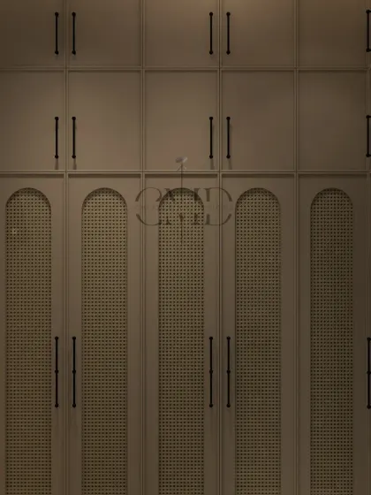 A close-up of the custom wardrobe with curved, cane-paneled shutters and textured molding, lit by a show-stopping chandelier.