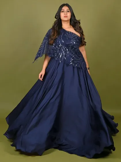 This elegant navy blue one-shoulder gown is a versatile choice for any formal event. The sequined bodice and flowing satin skirt create a sophisticated look for cocktail parties, receptions, or corporate award shows.