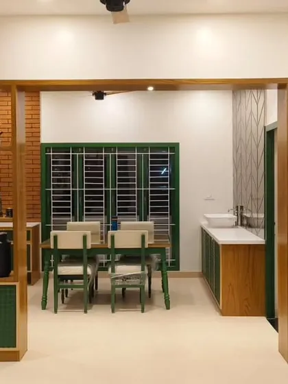 This project showcases a beautiful blend of textures, with a brick accent wall and a wooden partition separating the dining area. The use of green on the dining chairs and window frames adds a refreshing pop of color.