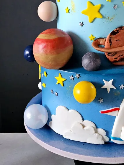 A detail shot of the space-themed cake, focusing on the hand-painted texture of the edible planets. I use different techniques to give each planet a unique and realistic appearance.