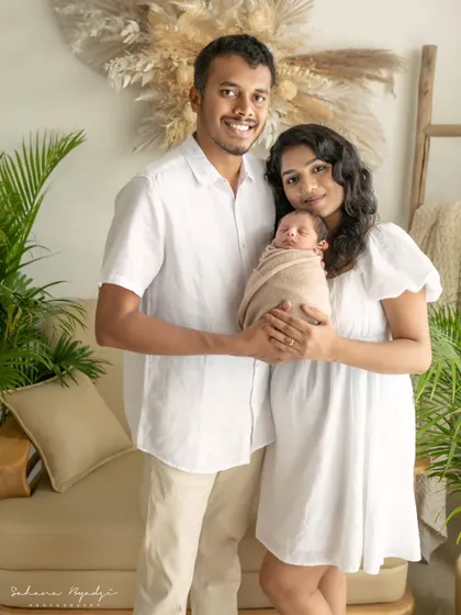 A lovely portrait of new parents with their newborn. The natural, earthy tones of the studio and their outfits create a warm and inviting atmosphere for their first family photo.