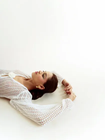 A serene and artistic shot on a clean white background. The negative space and the model's peaceful expression create a beautiful, minimalist composition.