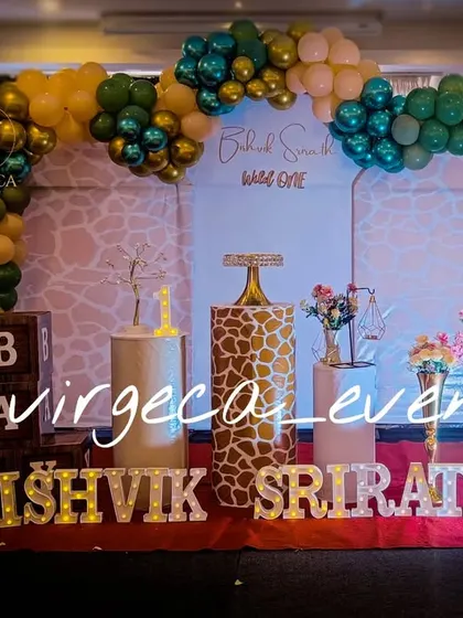 A 'Wild One' jungle theme with a touch of glam. The giraffe-print pedestal and gold and green balloons create a stylish safari vibe for this first birthday.