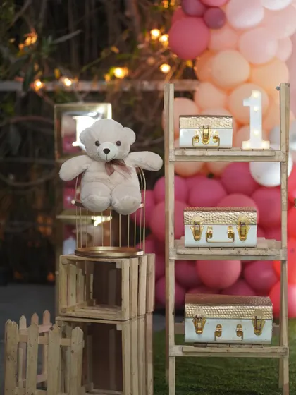 I use a variety of props to bring a theme to life, like this teddy bear in a birdcage and decorative vintage-style trunks. These details add texture and interest to the setup.