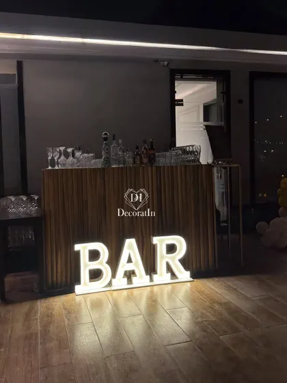 A close-up of the sleek, modern bar counter, highlighted by the glowing marquee letters.