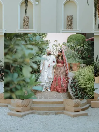 An artistic shot of the couple walking through a courtyard, framed by foreground elements to create depth.