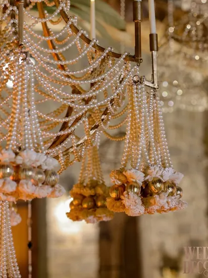The exquisite craftsmanship of our pearl and floral chandelier. This close-up shows the hand-strung pearls, delicate fabric flowers, and small golden baubles that make this piece so special.