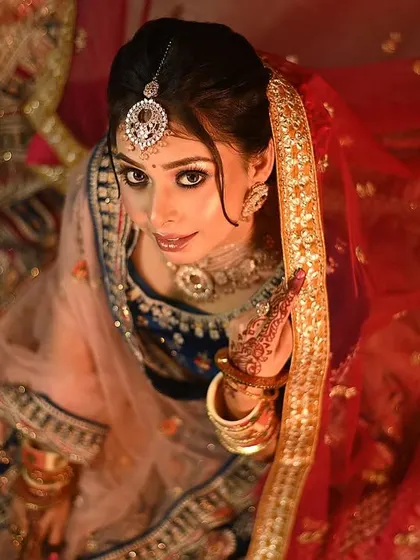 A creative angle for a unique bridal portrait. This top-down view captures the bride's confident gaze and the beautiful spread of her lehenga, creating an artistic and memorable shot.
