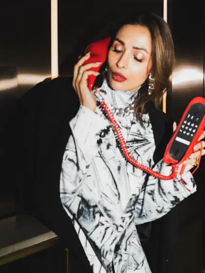 Malaika Arora in a candid moment with the red phone prop. These unposed shots often have the most personality.