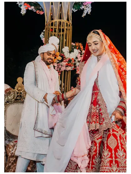 A moment of shared laughter and connection during the wedding ceremony. The groom helps his bride, showcasing a partnership that is already strong and supportive.