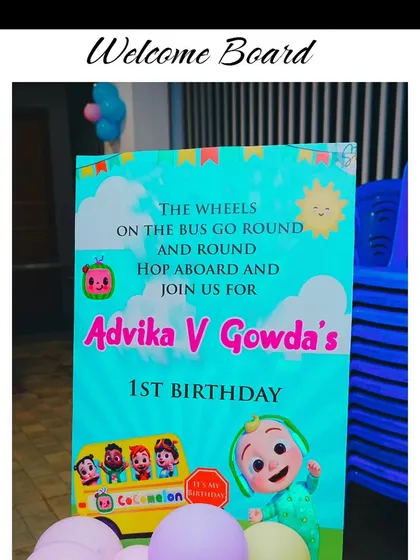 A bright and cheerful welcome board for Advika's Cocomelon-themed first birthday. The sign features lyrics from the show and invites guests to "hop aboard and join us for fun."