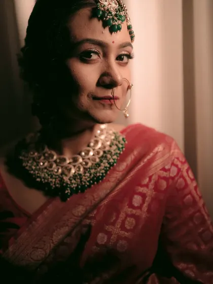 A close-up portrait of a bride in her red saree, her direct gaze full of confidence and grace.
