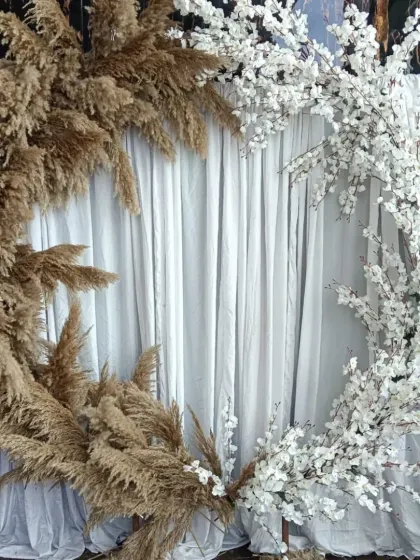 This view shows the full structure of the half-and-half pampas grass and flower backdrop, a great option for a rustic or boho-themed event.